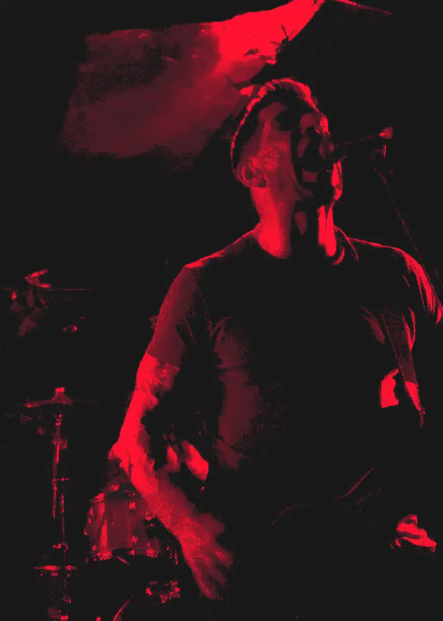 Paul performing live for Worship Pain under deep red light